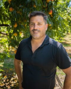 Justin Micheli head shot standing in peach orchard