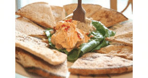 A plate with hummus and pita bread on it.