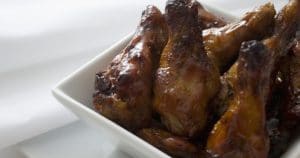 Chicken wings in a white bowl on a table.