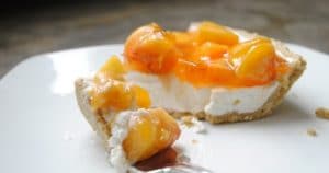 A slice of peaches and cream cheesecake on a plate with a fork.