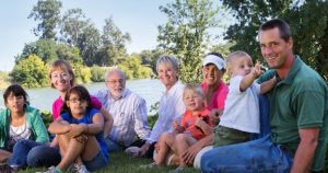 The Hemly Family lounges on the grassy bank of a river.