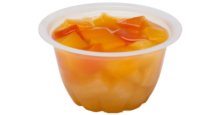 A cup of orange juice with canned fruit in it.