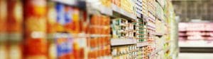 A row of cans containing canned fruits and tomatoes in a grocery store, catering to retailers.