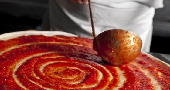 A pizza with red sauce made from resources.