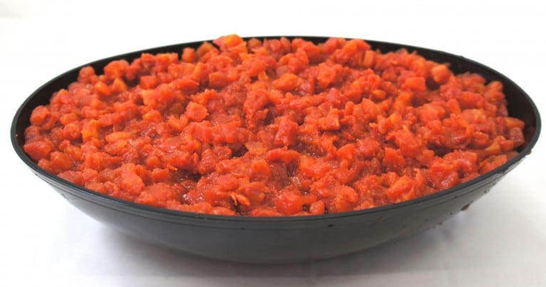 A bowl of carrots in a black bowl on a white surface.
