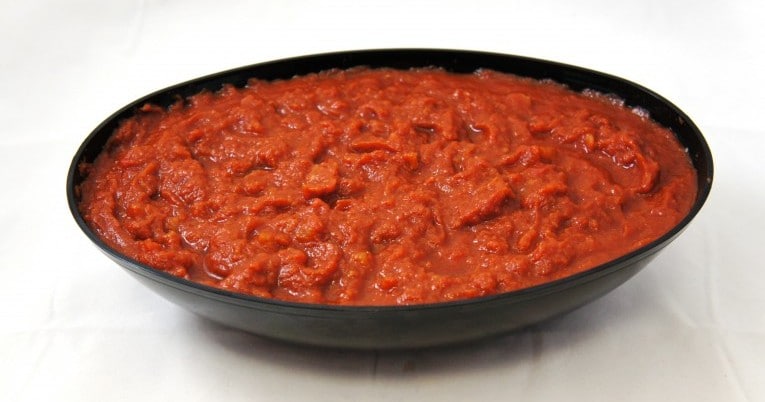Marinara pasta sauce in a bowl on a white surface.