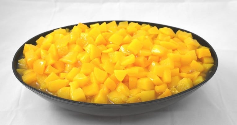 Mangoes in a bowl on a white surface.