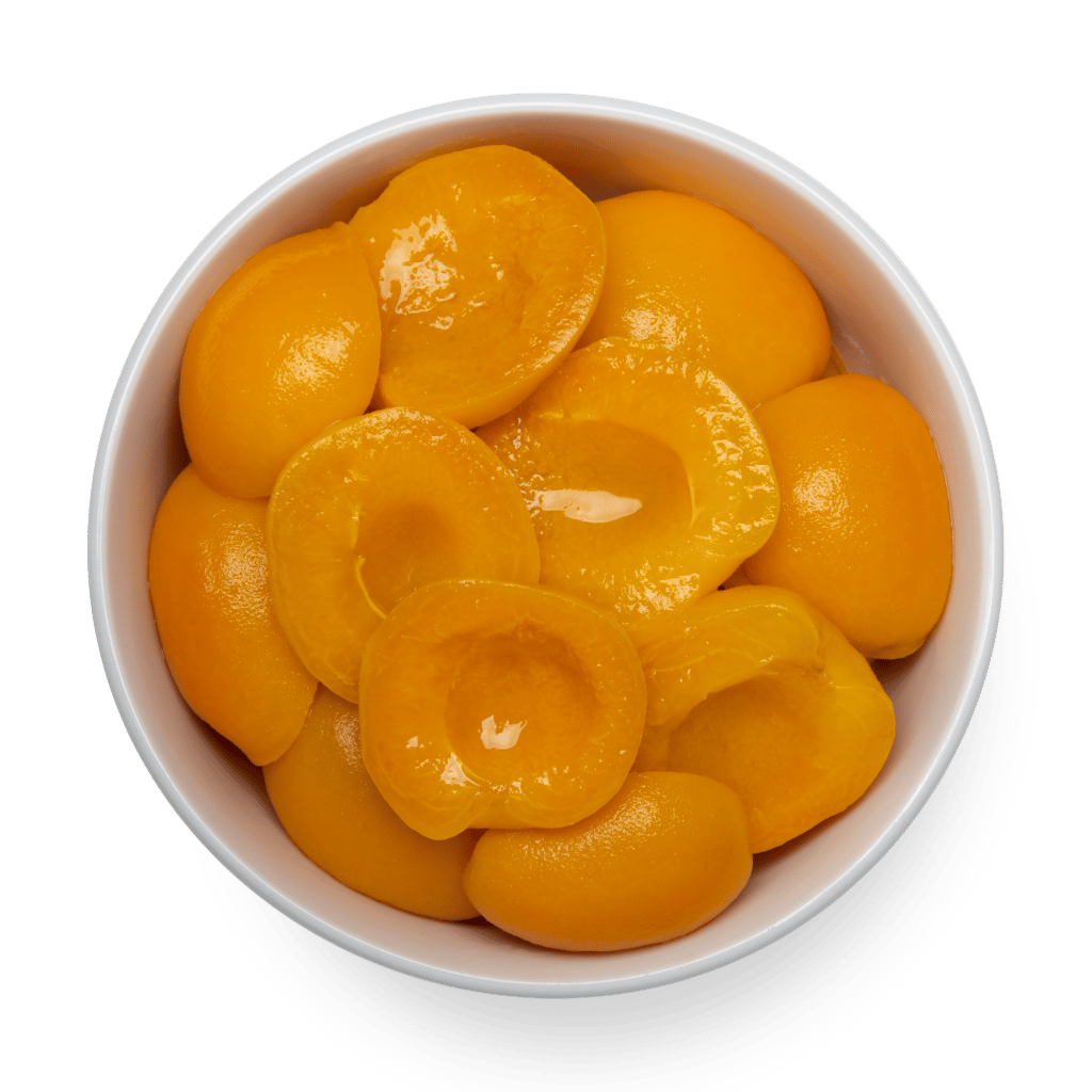 canned peach halves in a white bowl overhead view