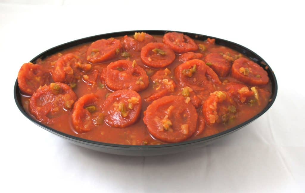 A black bowl filled with stewed tomatoes.