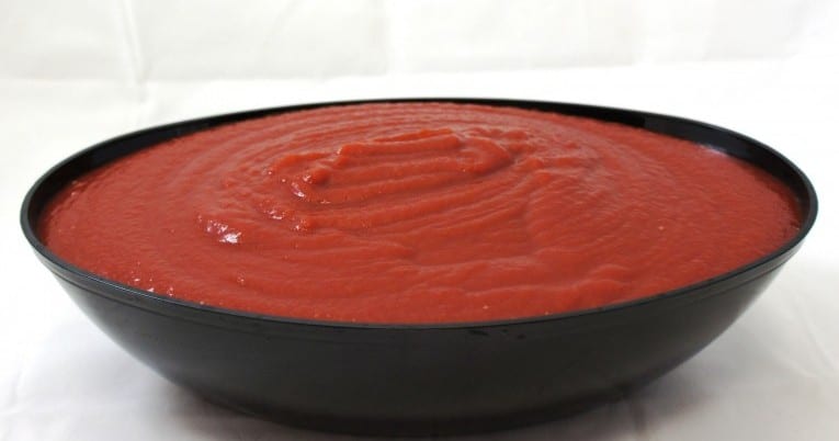A bowl of tomato sauce featuring #10 Standard Tomato Ketchup on a white surface.