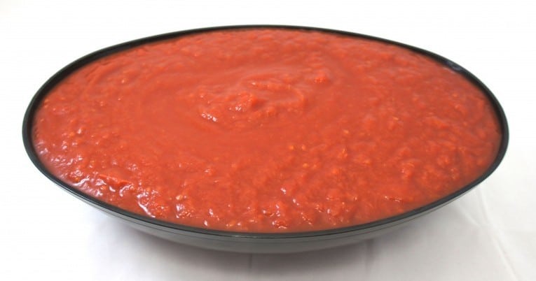 Tomato sauce featuring #10 Ground Peeled Tomatoes, showcased in a bowl on a white background.