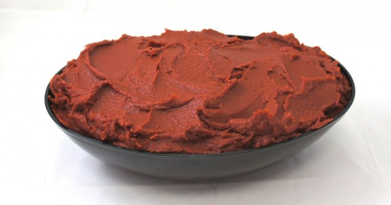 A bowl of organic tomato sauce in a black bowl.