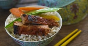 A bowl of Asian-inspired rice and vegetables with chopsticks.