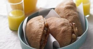 A bowl filled with breakfast pastries and orange juice.