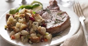 A plate with cranberry-pork chops and cranberry stuffing, accompanied by Pacific Northwest Pear and Cranberry Dressing.