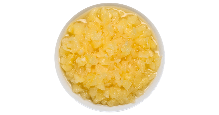 A white bowl of crushed pineapple chunks in heavy syrup on a green background.