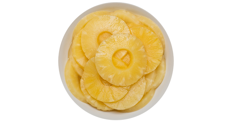 Canned pineapple slices in heavy syrup arranged in a bowl on a clean white background.
