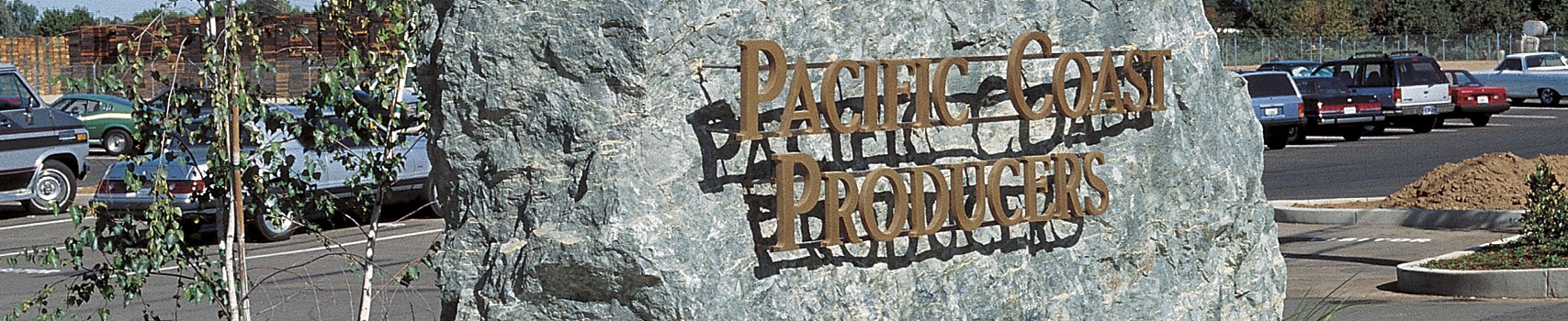 A large stone sign in front of a parking lot near the Pacific Coast Producers corporate office.