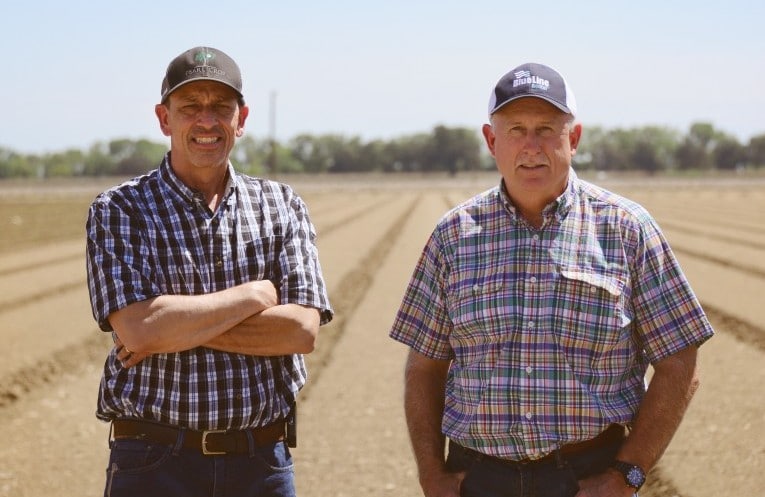 Two men standing in front of a plowed field at Payne Brothers Ranch.