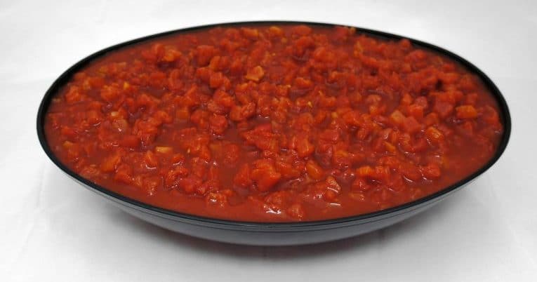 A bowl of tomato sauce made with #10 Petite Diced Tomatoes in Puree on a white surface.
