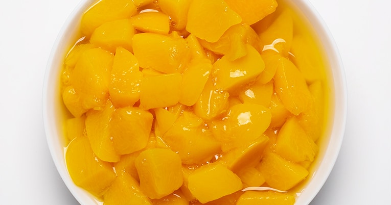Sliced mangoes in a bowl on a white background.