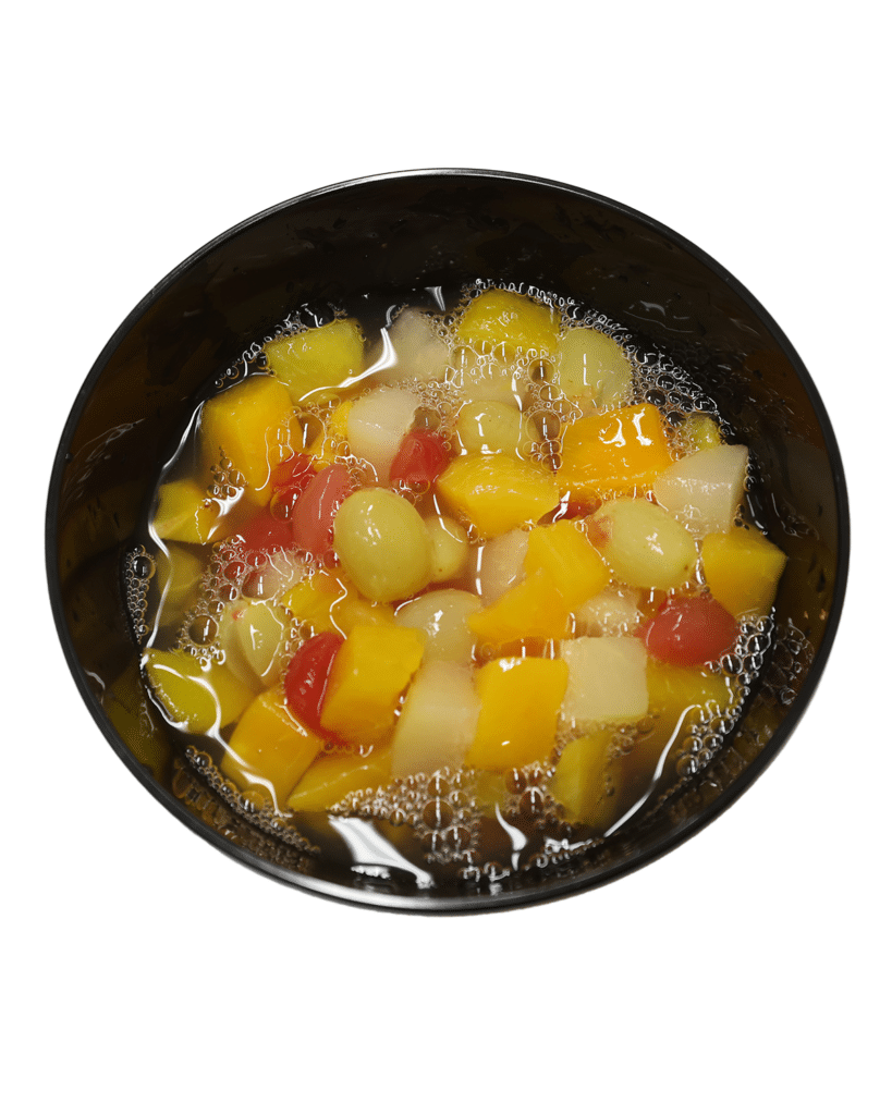 A Fruit Cocktail in Extra Light Syrup served in a black bowl on a white background.