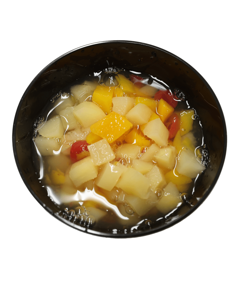 A fruit cocktail in a black bowl on a white background.