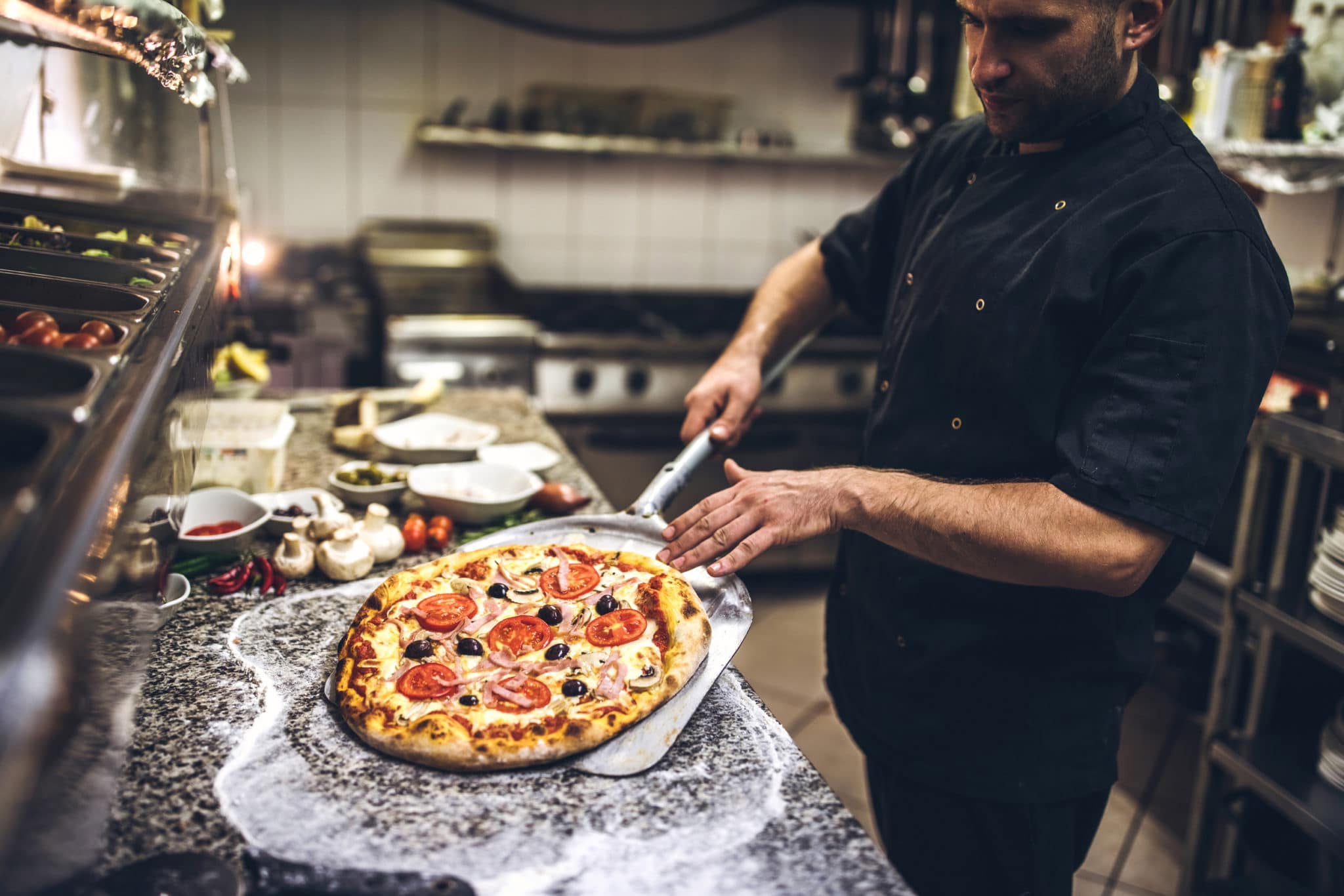A chef preparing a pizza using foodservice products.