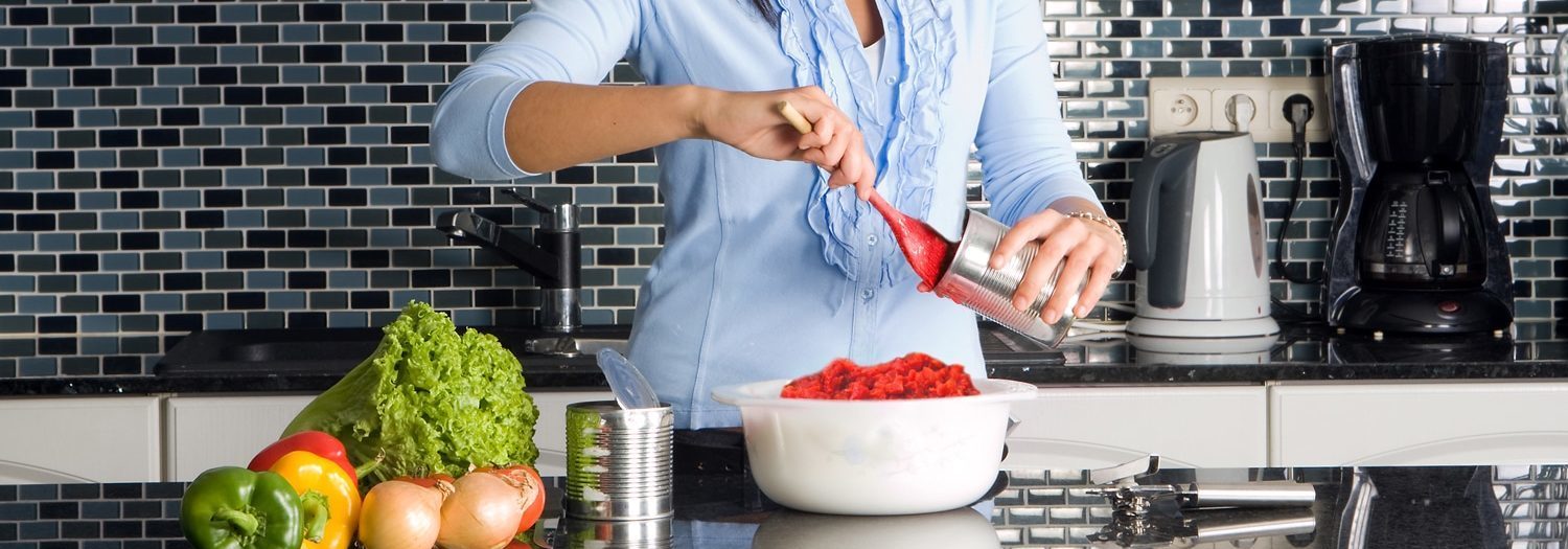 A woman is chopping vegetables with retail products in a kitchen.