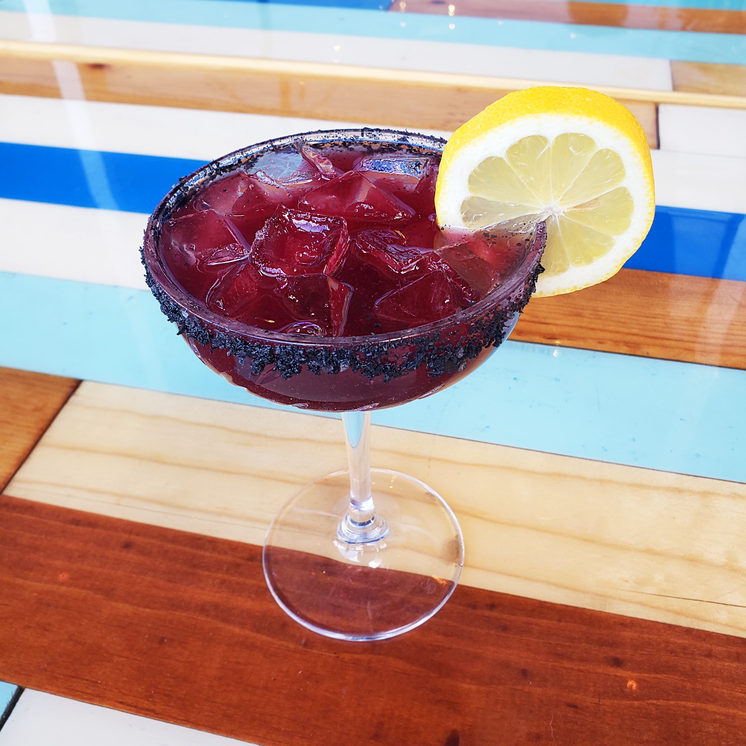 A Purple Pearl margarita with a lemon wedge on top.