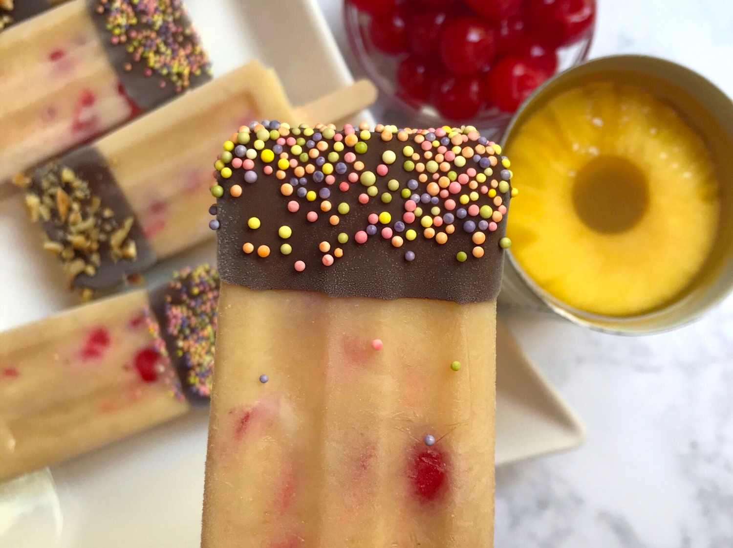 Banana "Split" Popsicles with sprinkles on a plate.