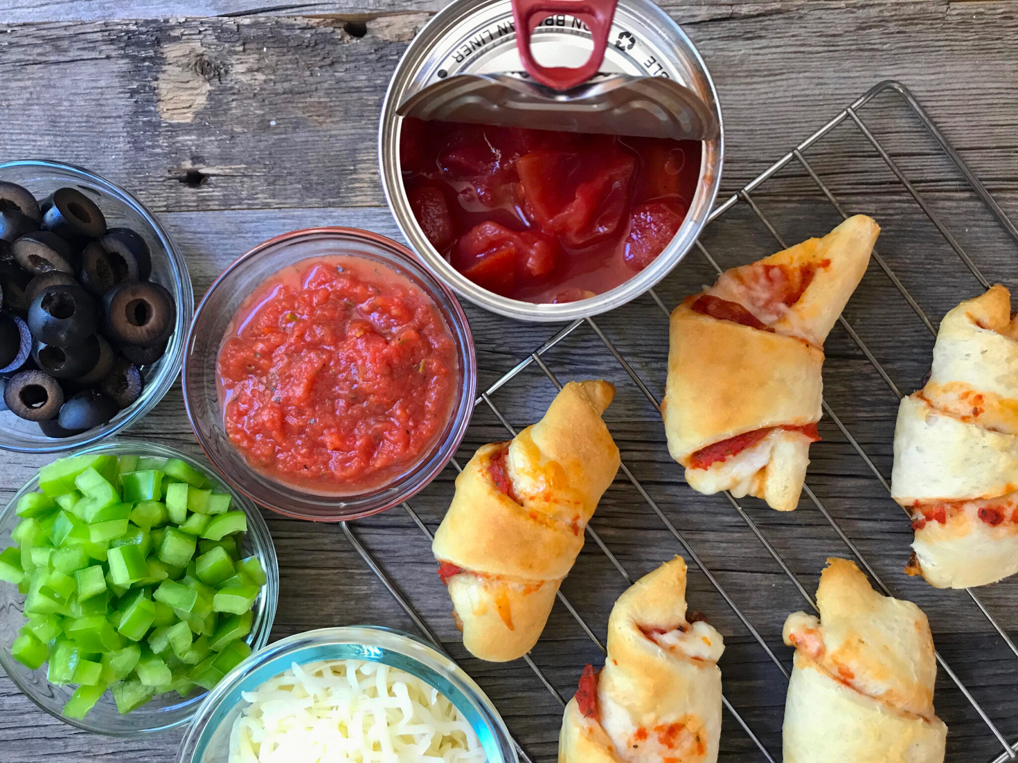 Pizza crescent rolls on a wooden table topped with homemade marinara.