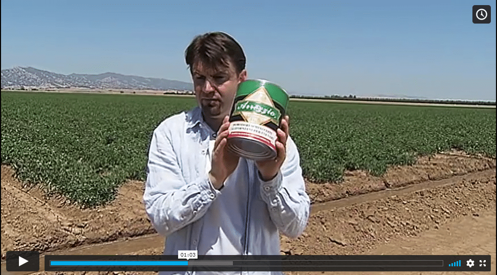 A man demonstrating Sysco's sustainability initiatives by showcasing a can in a field during a short training video.