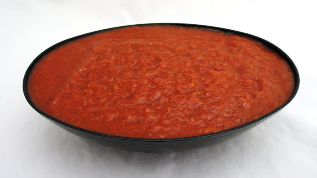Tomato sauce in a bowl on a white surface with organic diced tomatoes.