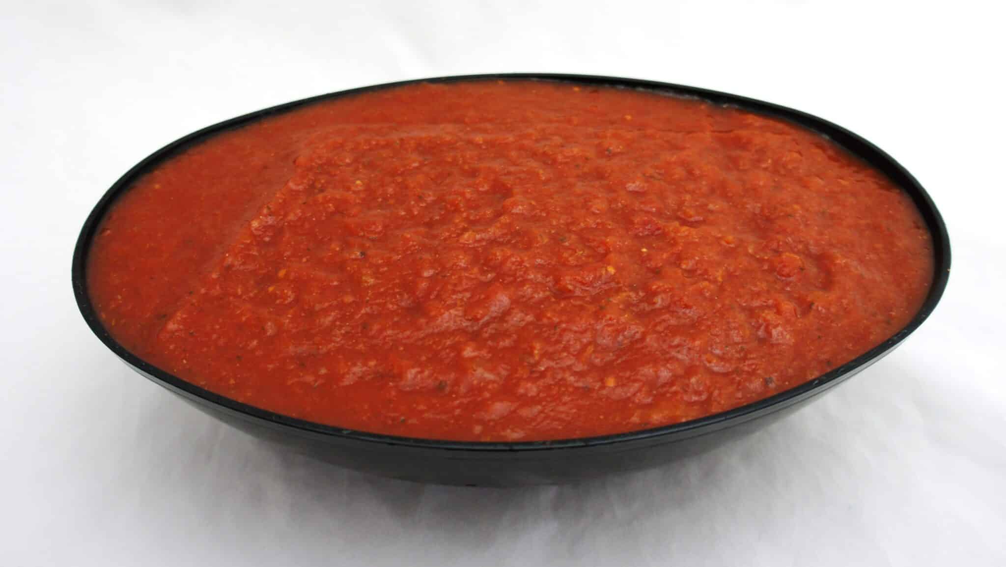 Tomato sauce in a bowl on a white surface with organic diced tomatoes.