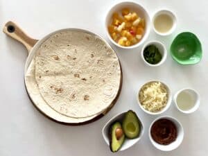 The ingredients for making a quesadilla are laid out on a white surface.