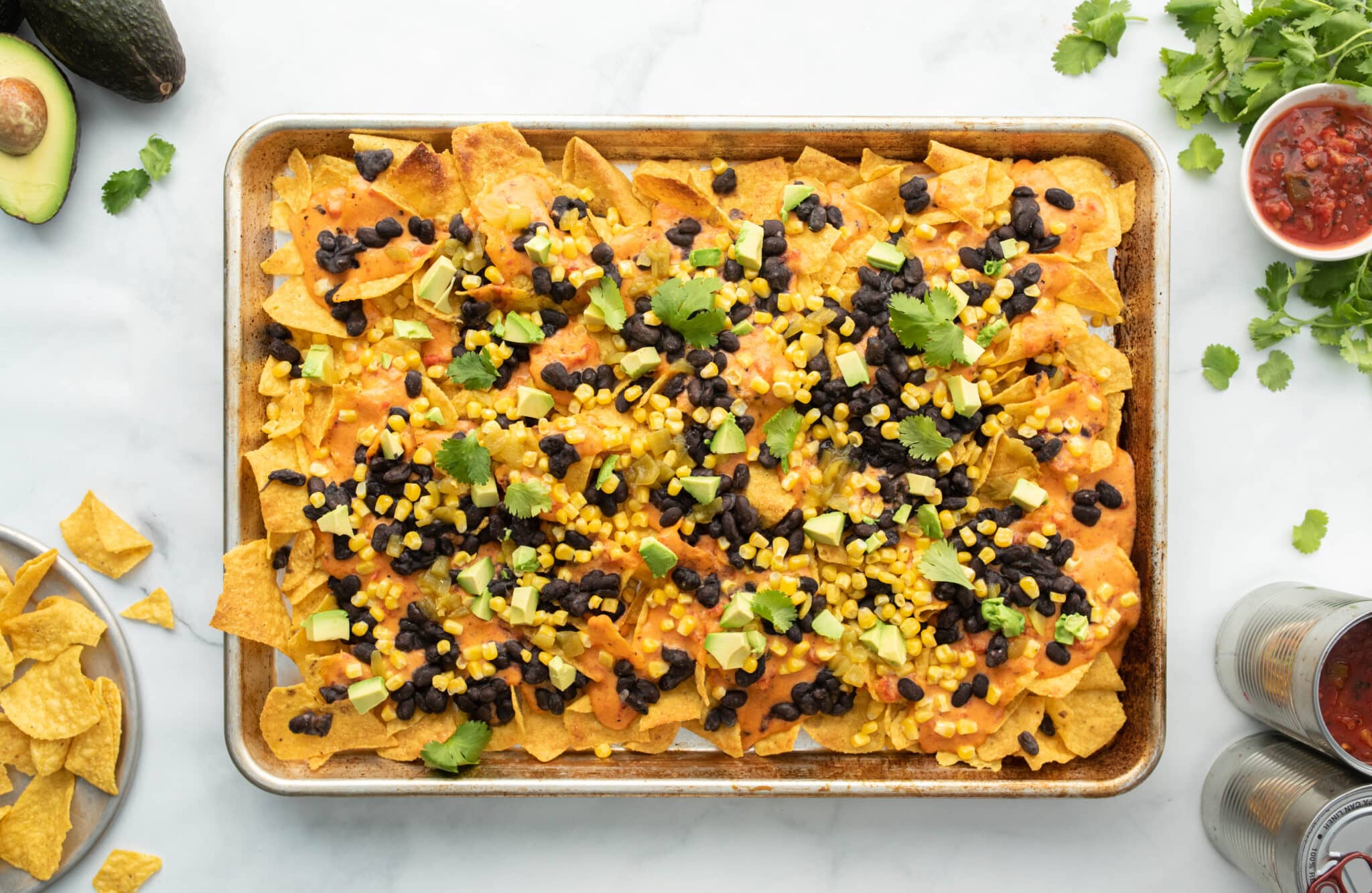 A tray of nachos with black beans, corn and avocado.