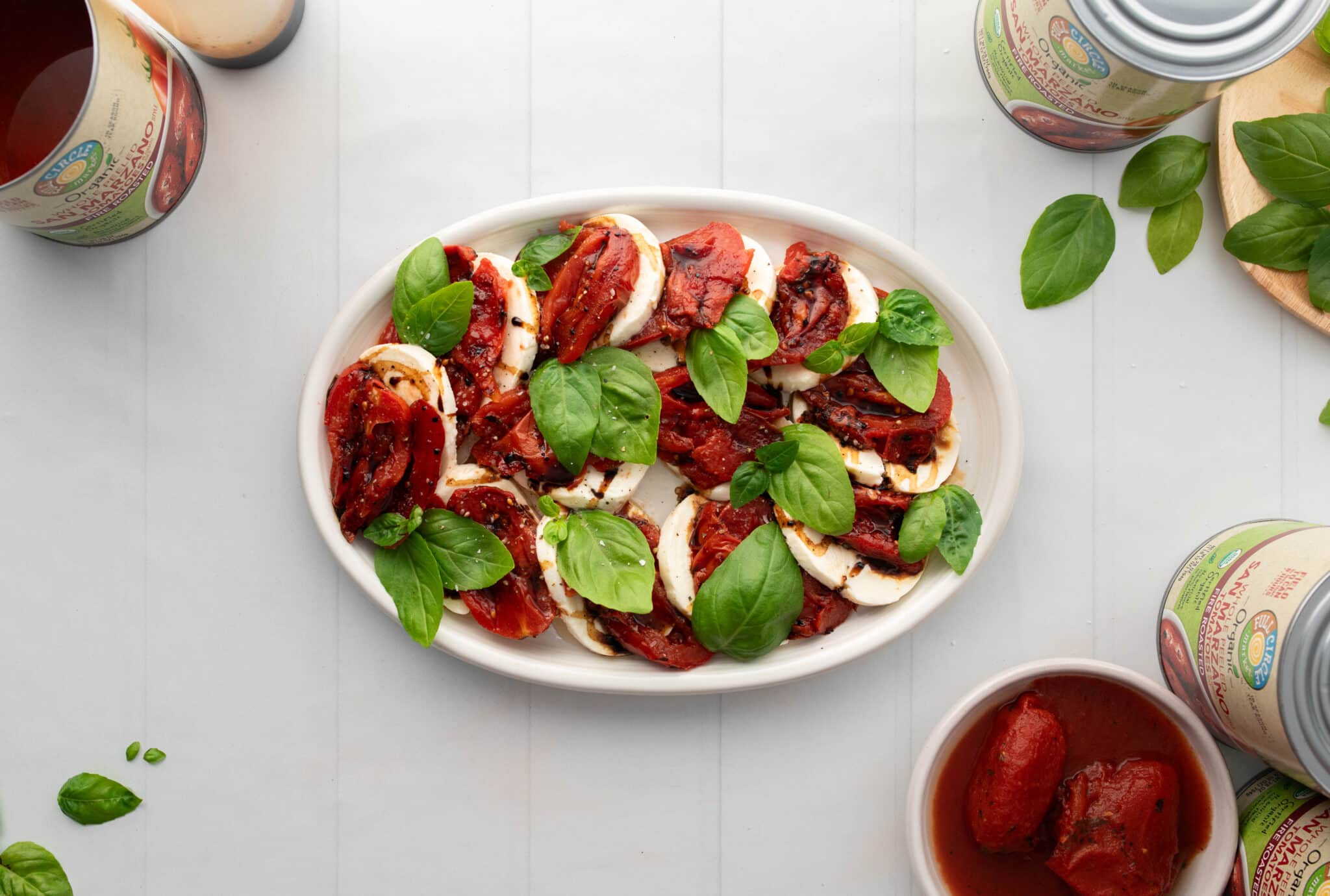 A plate with tomatoes, basil, and a bottle of balsamic vinegar.
